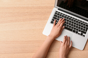 Female hands with modern new laptop on wooden background