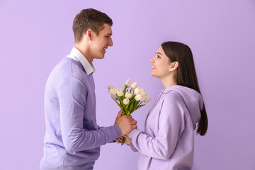 Sticker - Happy young couple with tulips on lilac background