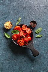 Bowl with tasty grilled tomatoes and basil on dark background