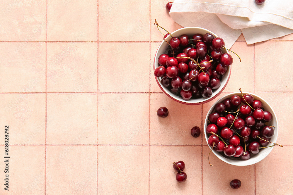 Bowls with sweet cherries on pink tile table