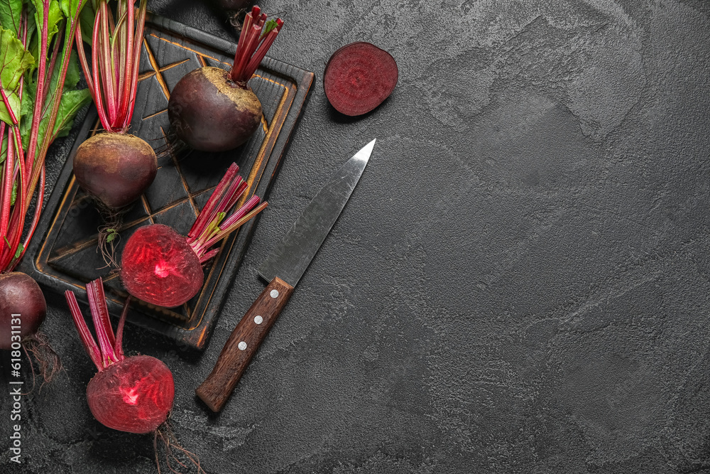 Wooden board of fresh beets on black background