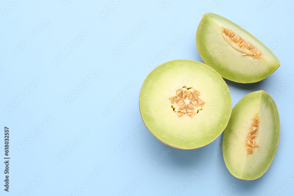 Half of sweet melon with pieces on blue background