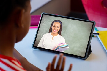 Poster - Diverse schoolboy with happy female teacher having class during tablet video call