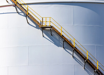 Wall Mural - White oil storage fuel tanks at depot station with access ladder against. Vertical fuel tank staircase.Curve line spiral staircase on storage fuel tank.Maintenance ladder on a oil storage tank..