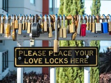 Steel gate adorned with multiple love locks and a cautionary sign attached to the center