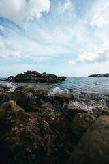 Poster - Stunning view of the ocean with its waves crashing against the rocks on a sunny day