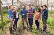 © Robert Kneschke - Smiling multiracial farmers standing with tools at greenhouse