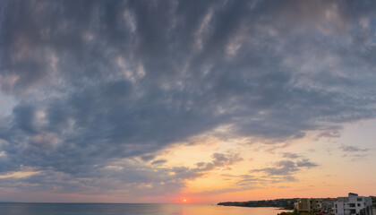 Wall Mural - dramatic dawn at the sea. gray clouds on the sky with red sun above the horizon. summer holidays rai