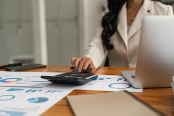 Wall Mural - Close-up of businesswoman hands using a calculator to check company finances and earnings and budget. Business woman calculating monthly expenses, managing budget, papers, loan documents, invoices