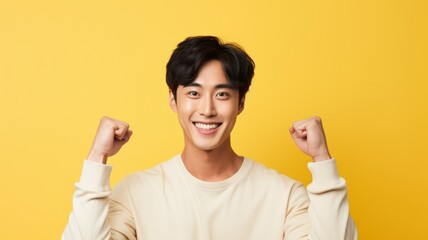 Portrait of a fictional young Korean guy in a happy victory pose. Isolated on yellow background. Generative AI illustration.