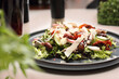 Salad with vegetables, cheese, olives, balsamic vinegar. Fresh healthy lunch on a black plate, selective focus.