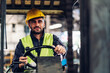 © kanpisut - Man worker at forklift driver happy working in industry factory logistic ship. Man forklift driver in warehouse area. Forklift driver sitting in vehicle in warehouse.