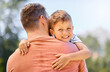 © HockleyMedia/peopleimages.com - Portrait, father and son hug, outdoor and smile with quality time, bonding and loving together. Face, dad and male child with happiness, kid and parent embrace, park and care with joy and support