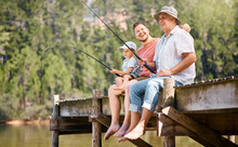 Happy Father, Grandfather And Child Fishing At Lake Together For Fun Bonding Or Peaceful Time In Nature. Dad, Grandpa And Kid Enjoying Life, Catch Or Fish With Rod By Water Pond Or River In Forest