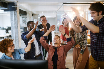 Group of young people celebrating a successful job in the office together