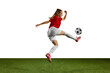 Dynamic image of female athlete, young girl, football player in motion with ball on sports field against white background. Concept of professional sport, action, lifestyle, competition, training, ad