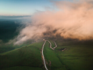 Wall Mural - Road in the green hills at foggy sunrise. Gil-Su valley in North Caucasus, Russia.