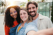 © Jose Calsina - Three young adult friends smiling taking a selfie portrait and having fun together. Group of multiracial cheerful people celebrating their friendship. Two women and one man with positive expression