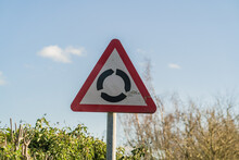Triangle UK Roundabout Sign Against Blue Sky With Clouds, Information, Travel And Tourism Concept Illustration.