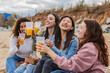 © PintoArt - group of diverse female friends having drink on the beach