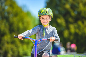 Wall Mural - boy with helmet riding his scooter on a sunny day