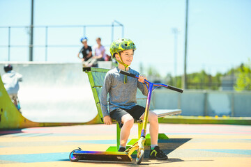 Wall Mural - boy with helmet riding his scooter on a sunny day