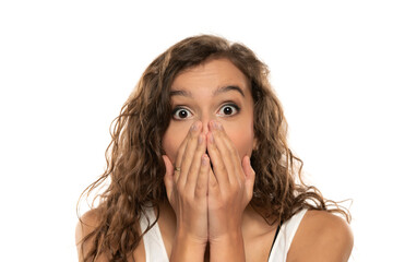 Shocked young woman covering mouth with hands isolated on white background