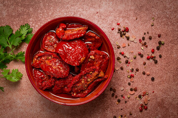 dried tomatoes, in a bowl, top view, on a brown background,