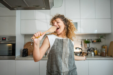 Wall Mural - One happy young adult caucasian woman wear apron in the kitchen smile