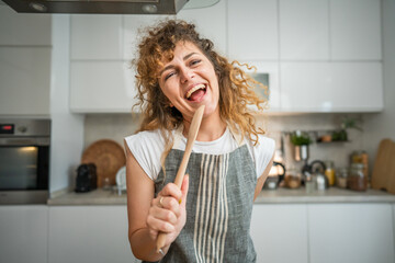 Wall Mural - One happy young adult caucasian woman wear apron in the kitchen smile