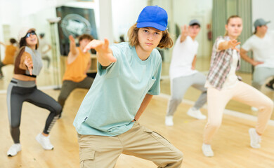 Wall Mural - Group of positive teenagers dancing modern hip-hop dance in studio.