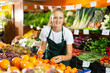 © JackF - Cheerful young girl employees in uniform holding fresh mandarines in grocery shop