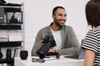 © New Africa - Young professional photographer holding camera while talking with woman in modern photo studio