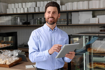 Wall Mural - Happy business owner with tablet in bakery shop