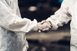 © kanpisut - Scientist wear Chemical protection suit shaking hands.  Scientist working at dangerous zone