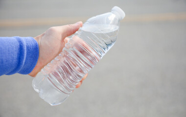  hand tightly gripping a plastic water bottle, symbolizing the environmental impact and urgency to reduce single-use plastic waste