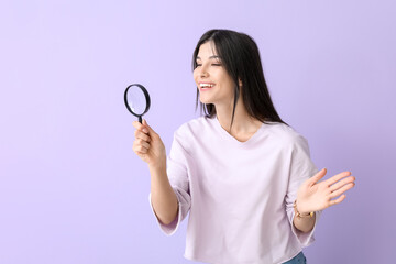 Beautiful happy young woman with magnifier on lilac background