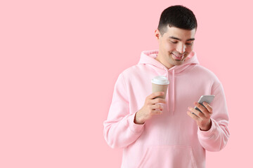 Canvas Print - Young man with smartphone and coffee on pink background