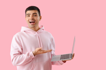 Poster - Happy young man with laptop on pink background