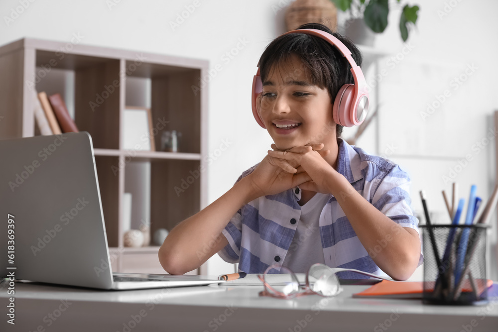 Little boy in headphones studying at home