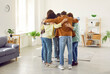 Group of a happy young friends men and women standing in circle and having fun at home, hugging indoors and enjoying spending time together. Friendship, party and friends meeting concept.