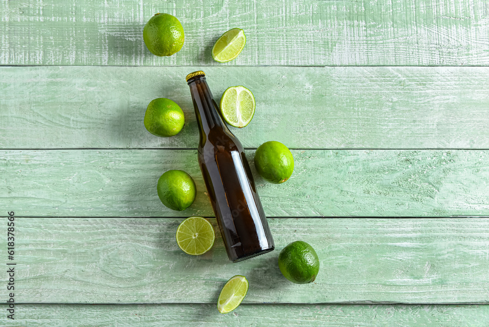 Bottle of cold beer with lime on green wooden background