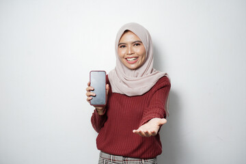 Wall Mural - Amazed young Asian Muslim woman showing mobile phone blank screen recommending App isolated over white background