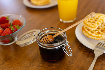 Wall Mural - Close up of strawberries, jam, waffles and juice on wooden table