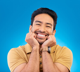Poster - Happy, excited man and cute smile portrait in studio with Asian model with teeth and joy. Blue background, male person and casual fashion with handsome and friendly guy with modern style and wow face