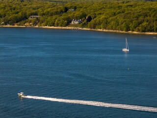 Canvas Print - Aerial view over the calm waters with a sailboat traveling in Oyster Bay near Lloyd Harbor, New York