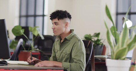 Wall Mural - happy biracial male creative using tablet and computer at casual office, in slow motion