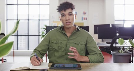 Wall Mural - portrait of biracial male designer in video call at computer in casual office, slow motion