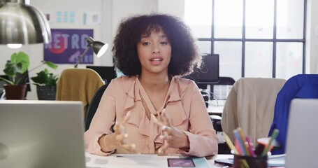 Wall Mural - portrait of african american female designer in video call at computer in casual office, slow motion