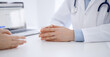 © rogerphoto - Doctor and patient discussing current health questions while sitting opposite of each other at the table in clinic, just hands closeup. Medicine concept